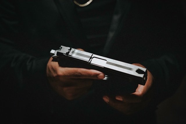 Closeup of a man dressed in all black holding a gun.